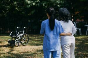 junge asiatische physiotherapeutin, die mit einer älteren frau beim gehen mit einer gehhilfe arbeitet foto