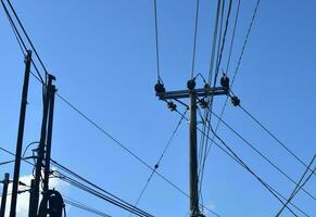 Elektrizität Stangen mit viele von Drähte aussehen Laufen über gegen Blau Himmel foto