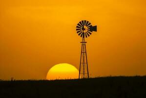 ein Windmühle und ein Sonnenuntergang im das Hintergrund foto