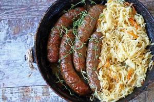 bayerische Würstchen in der Pfanne mit gedünstetem Sauerkraut oktoberfest Essen foto