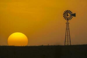 ein Windmühle und ein Sonnenuntergang im das Hintergrund foto