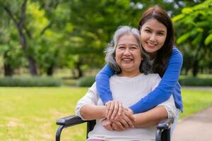 asiatische Pflegekraft oder Krankenschwester, die sich um den Patienten im Rollstuhl kümmert. Konzept des glücklichen Ruhestands mit Betreuung durch eine Pflegekraft und Spar- und Seniorenkrankenversicherung, eine glückliche Familie foto