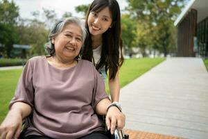 asiatisch Vorsichtig Pflegekraft oder Krankenschwester nehmen Pflege von das geduldig im ein Rollstuhl. Konzept von glücklich Pensionierung mit Pflege von ein Pflegekraft und Ersparnisse und Senior Gesundheit Versicherung, ein glücklich Familie foto