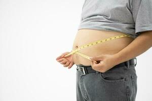 Übergewicht Mann Verwendet ein Messung Band zum Maße seine Fett Bauch. isoliert auf Weiß Hintergrund. Konzept von Gesundheitspflege, Medizin, und Gewicht Verlust foto