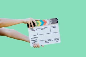 Hand, die Filmschieferfarbentafel für Filmkino und Fernsehindustrie auf grünem Hintergrund hält foto
