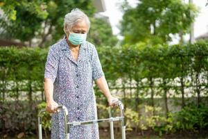 Asiatische Senioren oder ältere alte Damen gehen mit Walker und tragen eine Gesichtsmaske zum Schutz der Sicherheitsinfektion und zum Abtöten des neuartigen Coronavirus Covid-19-Virus.