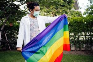 asiatische dame, die regenbogenfarbenfahne hält, symbol des lgbt-stolzmonats, feiert jährlich im juni sozial für schwule, lesbische, bisexuelle, transgender, menschenrechte foto