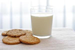 Haferkekse mit Glas Milch zum Frühstück auf Tischdecke und blaue Blume im Hintergrund, rustikales gesundes Essen foto