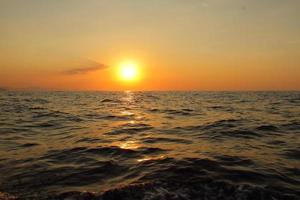 orange heller Sonnenuntergang unter dem Ozean. Sonnenreflexion auf dem Wasser landschaftlich, gelbe Dämmerung, friedliche Naturlandschaft foto