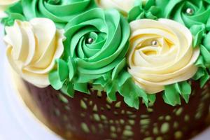 hausgemachter wunderschöner Kuchen mit gelben und grünen Rosen aus Buttercreme, Schokoladenrahmen, Zuckerguss auf weißem Hintergrund foto