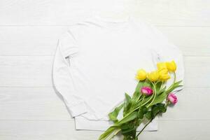 Nahansicht Weiß leer Vorlage Sweatshirt Kapuzenpullover Kopieren Raum. Mütter Frauen Tag Gelb Tulpen, Rosa Rosen Geschenke. glücklich Geburtstag oben Aussicht Attrappe, Lehrmodell, Simulation zur Seite fahren. Weiß hölzern Hintergrund. eben legen Vorlagen foto