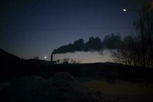 Rauch von Kamin beim Sonnenuntergang. Abend Landschaft mit Fabrik. Rauch im Himmel. foto