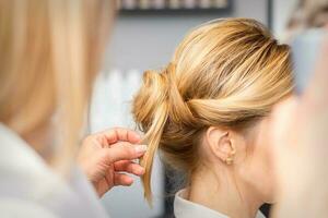 Nahansicht Friseur Styling blond Haar auf das zurück von das Kopf im ein Schönheit Salon. foto