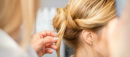 Nahansicht Friseur Styling blond Haar auf das zurück von das Kopf im ein Schönheit Salon. foto