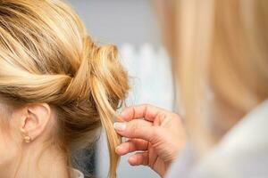 Nahansicht Friseur Styling blond Haar auf das zurück von das Kopf im ein Schönheit Salon. foto