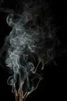 kreative Illustration des Räucherstäbchenaromas mit Rauch isoliert auf schwarzem Hintergrund foto