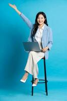 asiatisch Geschäftsfrau Porträt Sitzung auf Stuhl, isoliert auf Blau Hintergrund foto