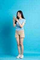 voll Körper Bild von schön asiatisch Mädchen posieren auf Blau Hintergrund foto
