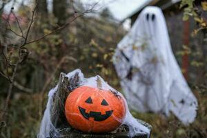 Halloween Kürbislaterne auf ein alt Stumpf im das Wald gegen das Hintergrund von ein Geist foto