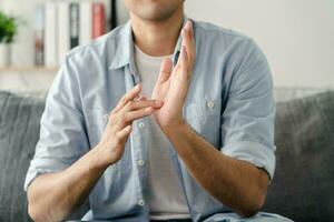 glücklich jung taub Mann mit Zeichen Sprache zu kommunizieren mit andere Personen. foto