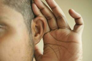 junger Mann mit Ohrenschmerzen, der sein schmerzendes Ohr berührt, foto