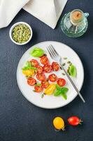 fertig für den Verzehr Vegetarier Lebensmittel. getrocknet Tomaten mit Basilikum, Sesam Saat und Kürbis auf ein Teller auf ein schwarz Hintergrund. oben und Vertikale Aussicht foto