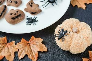 dekorieren das Tabelle mit Handarbeit zum Halloween. schwarz fliegen auf ein gestrickt Kürbis gegen das Hintergrund von Lebkuchen Kekse auf ein Platte. traditionell Feier foto