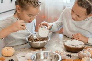 vorbereiten zu feiern Halloween und vorbereiten ein behandeln. zwei Mädchen bereiten Halloween Kekse im das Teig zum Backen beim Zuhause im das Küche. foto