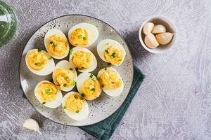 Eier gefüllt mit ein Mischung von Eigelb, Käse, Knoblauch und Mayonnaise auf ein Teller oben Aussicht foto