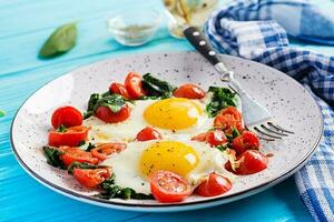 Teller mit ein Keto Diät Lebensmittel. gebraten Ei, Spinat, und Tomaten. Keto, Paläo Frühstück. foto
