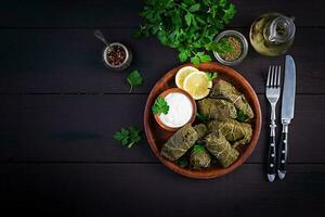 Dolma. ausgestopft Traube Blätter mit Reis und Fleisch auf dunkel Tisch. Mitte östlichen Küche. oben Sicht, Overhead, Kopieren Raum foto