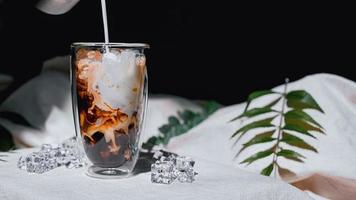 Barista gießt Milch in ein Glas Eiskaffee foto