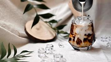 Barista gießt Milch in ein Glas Eiskaffee foto