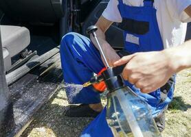 Mechaniker Sprühen Auto mit Wasser. Mechaniker Reinigung Auto mit Spritzgerät. foto