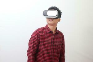 Porträt von asiatisch Mann im rot Plaid Hemd mit virtuell Wirklichkeit vr Brille und suchen hoch. isoliert Bild mit Kopieren Raum auf Weiß Hintergrund foto