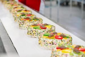 Kuchen dekorieren auf dem Förderband einer Süßwarenfabrik.