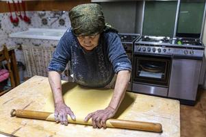 Oma rollt den frisch gekneteten Teig aus foto