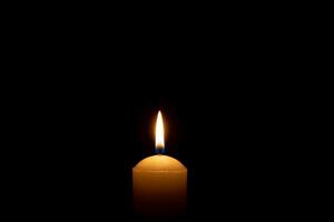 Single Verbrennung Kerze Flamme oder Licht glühend auf ein groß Weiß Kerze auf schwarz oder dunkel Hintergrund auf Tabelle im Kirche zum Weihnachten, Beerdigung oder Denkmal Bedienung mit Kopieren Raum. foto