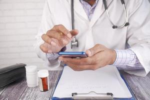 Arzt im weißen Kittel mit einem Smartphone foto
