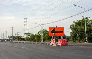 ein Aussicht von das Oberfläche von ein Neu schwarz Asphalt Straße mit Zeichen und Orange Barrikaden. foto