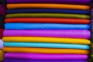 Künstlerische Vielfalt Schatten Ton färbt Textilstoffe, die im Ladenregal zum Verkauf gestapelt sind foto