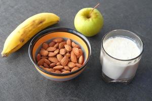 Mandelnuss, Banane, Apfel und Milch auf dem Tisch foto