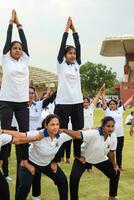 Neu Delhi, Indien, Juni 21, 2023 - - Gruppe Yoga Übung Session zum Menschen beim Yamuna Sport Komplex im Delhi auf International Yoga Tag, groß Gruppe von Erwachsene Teilnahme Yoga Klasse im Kricket Stadion foto