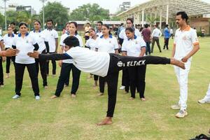 Neu Delhi, Indien, Juni 21, 2023 - - Gruppe Yoga Übung Session zum Menschen beim Yamuna Sport Komplex im Delhi auf International Yoga Tag, groß Gruppe von Erwachsene Teilnahme Yoga Klasse im Kricket Stadion foto