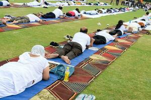 Neu Delhi, Indien, Juni 21, 2023 - - Gruppe Yoga Übung Session zum Menschen beim Yamuna Sport Komplex im Delhi auf International Yoga Tag, groß Gruppe von Erwachsene Teilnahme Yoga Klasse im Kricket Stadion foto