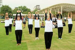 Neu Delhi, Indien, Juni 21, 2023 - - Gruppe Yoga Übung Session zum Menschen beim Yamuna Sport Komplex im Delhi auf International Yoga Tag, groß Gruppe von Erwachsene Teilnahme Yoga Klasse im Kricket Stadion foto