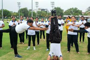 Neu Delhi, Indien, Juni 21, 2023 - - Gruppe Yoga Übung Session zum Menschen beim Yamuna Sport Komplex im Delhi auf International Yoga Tag, groß Gruppe von Erwachsene Teilnahme Yoga Klasse im Kricket Stadion foto