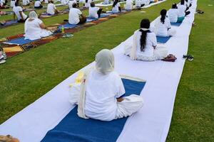 Neu Delhi, Indien, Juni 21, 2023 - - Gruppe Yoga Übung Session zum Menschen beim Yamuna Sport Komplex im Delhi auf International Yoga Tag, groß Gruppe von Erwachsene Teilnahme Yoga Klasse im Kricket Stadion foto