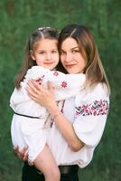 kaukasisch bezaubernd wenig Mädchen kuscheln ihr Mutter. ukrainisch National Kleidung, Stickerei, Traditionen foto
