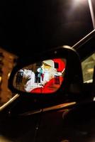 Weihnachtsmann spiegelt sich in einem Autospiegel